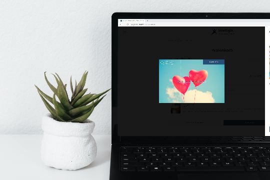 Tisch mit Laptop auf dem der Gutschein-Shop-Editor mit Bild-Upload geöffnet ist
