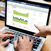 zwei Personen arbeiten an einem Laptop mit Qlik Sense