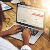 Frau sizt am Laptop und legt ein Dokument digital mit DocuWare ab