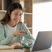 Eine Recruiterin führt einen Videocall in einem modernen Büro und macht Notizen