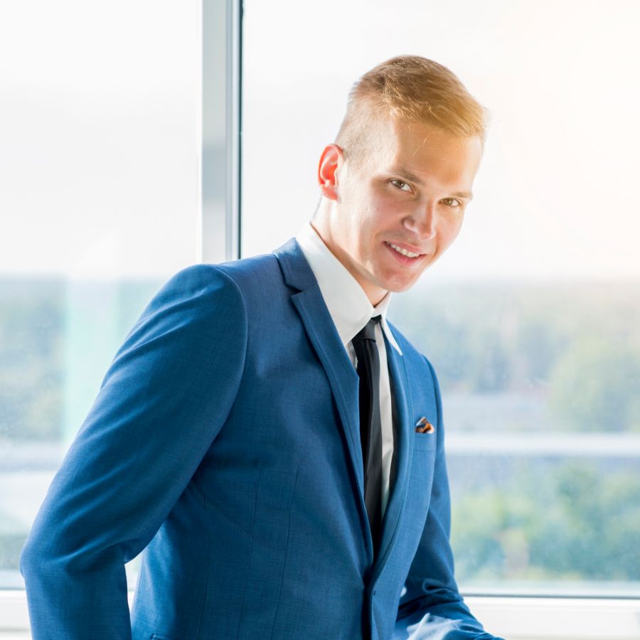 Ein professioneller Geschäftsmann im Anzug steht vor einem Fenster mit Blick auf die Stadt.