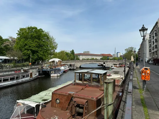 Die Spree in Berlin. Im Kanal sind mehrere Haus- und Lastenboote zu sehen. Am Rand stehen Mehrfamilienhäuser mit Eigentumswohnungen.
