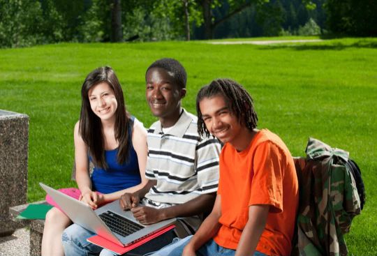 Drei Schüler der Oberstufe lernen im Park und bereiten sich während den Ferien auf die Prüfung vor