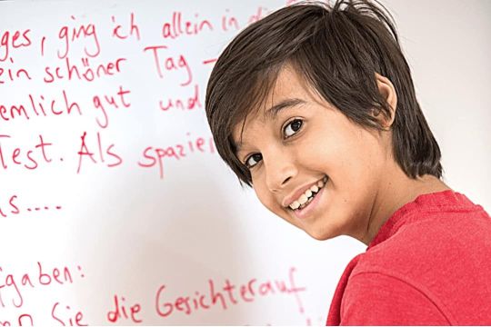 Schüler der Mittelstufe zeigt seinen Deutsch-Aufschrieb an einem Whiteboard während einer Nachhifestunde
