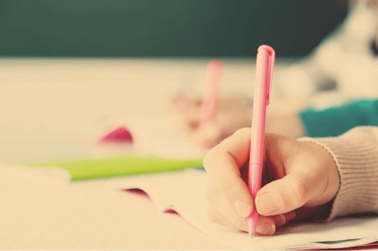 Die Hände von zwei Schülern schreiben fleißig und symbolisieren das intensive Lernen auf eine Abschlussprüfung