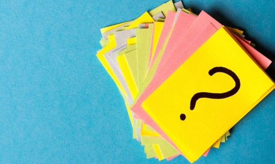 Stapel farbiger Karteikarten mit Fragezeichen auf der obersten Karte als Symbol für Fragen von Eltern