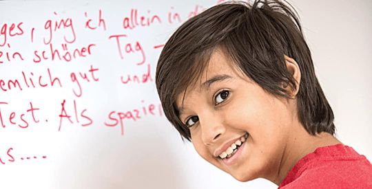 Schüler der Mittelstufe zeigt seinen Deutsch-Aufschrieb an einem Whiteboard während einer Nachhifestunde