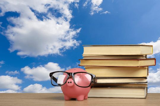 Sparschwein platziert vor Schulbüchern als Symbol für das Sparangebot "100 € Rabatt"